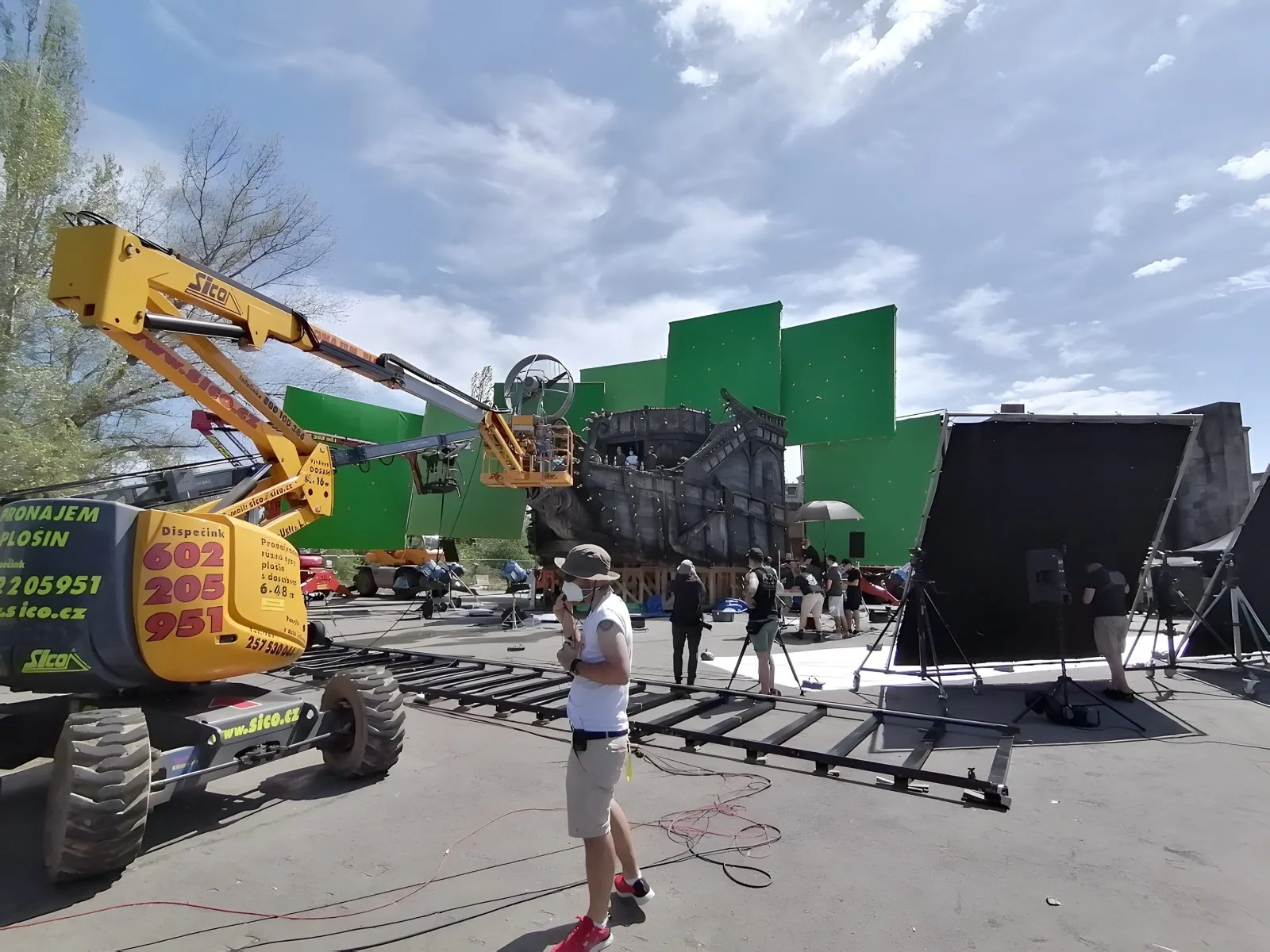 Backlot with green screens, a boom lift and set pieces on The Wheel of Time