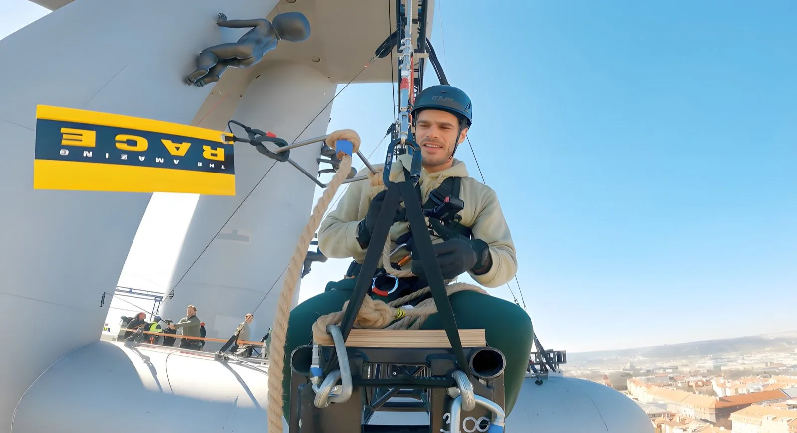 A racer clipped into a seat harness on the tower rigging